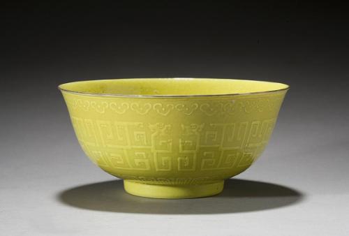 Lemon-yellow bowl with raised designs of stylized dragons