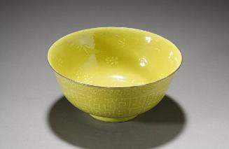 Lemon-yellow bowl with raised designs of stylized dragons