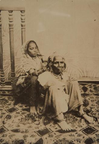 A seated girl tends to an elderly woman